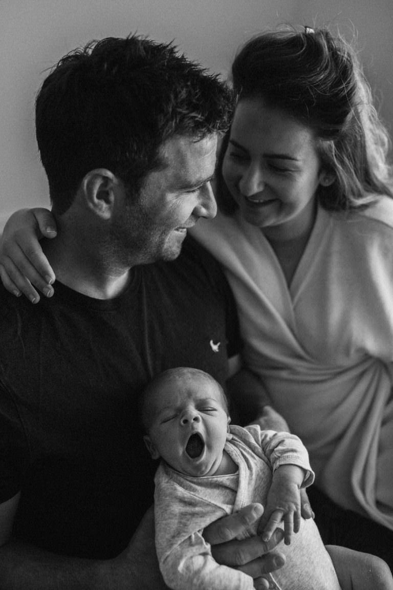 black and white new parents hold yawning baby